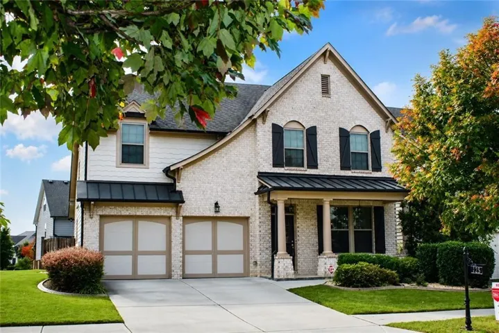 Brick and siding exterior with a gabled roofline, featuring a two-car garage, covered entry with columns, and mature landscaping