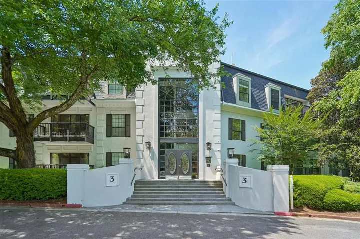 Stately white stucco exterior featuring a grand entrance with a two-story glass facade and ornate double doors