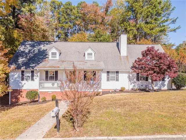 New england style home featuring a porch, a front yard, a chimney, and crawl space