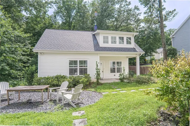 White siding exterior with a dark shingle roof and dormer windows