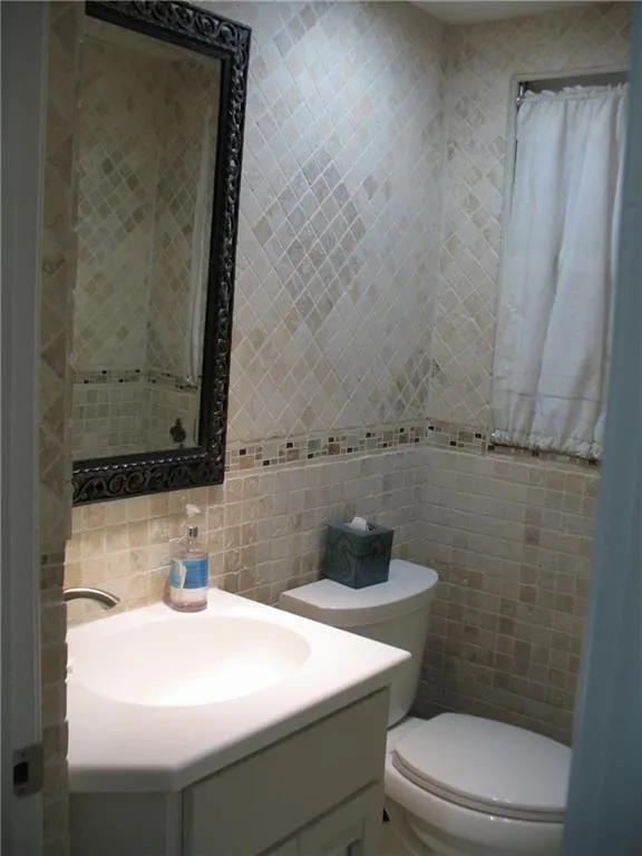 Full bathroom with tile walls, vanity, and backsplash