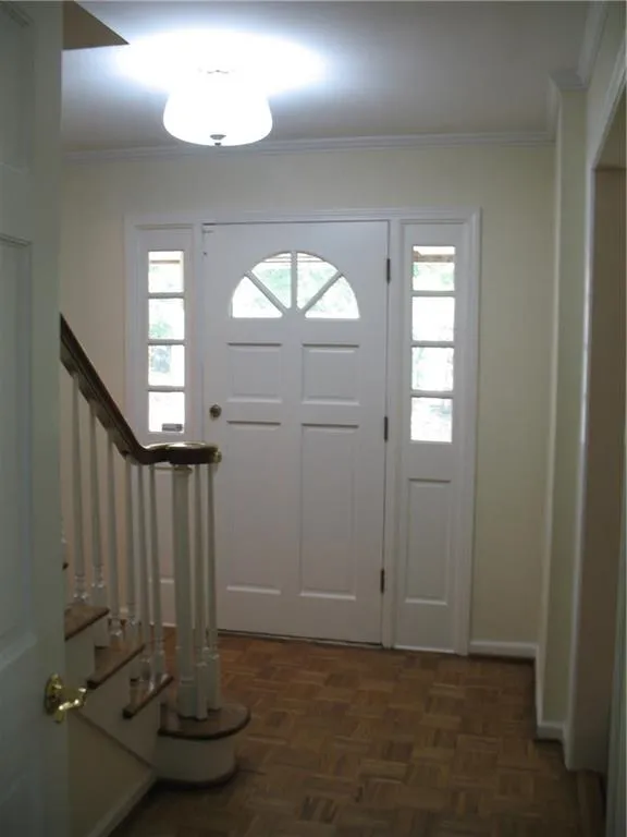 Foyer entrance with plenty of natural light, stairs, and crown molding