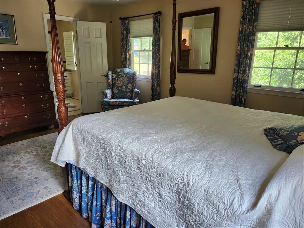 Bedroom with wood finished floors and multiple windows
