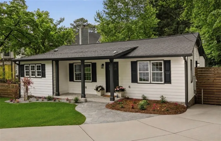 White siding exterior with a dark shingle roof, featuring a covered front porch with dark columns