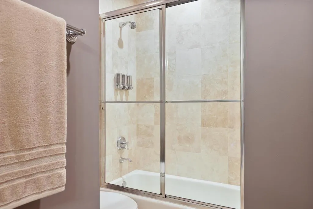 Bathroom featuring combined bath / shower with glass door and toilet