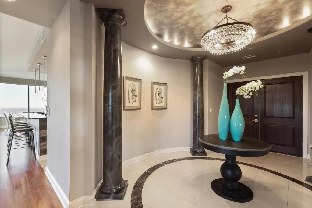 Hallway featuring a chandelier, tile patterned flooring, and ornate columns