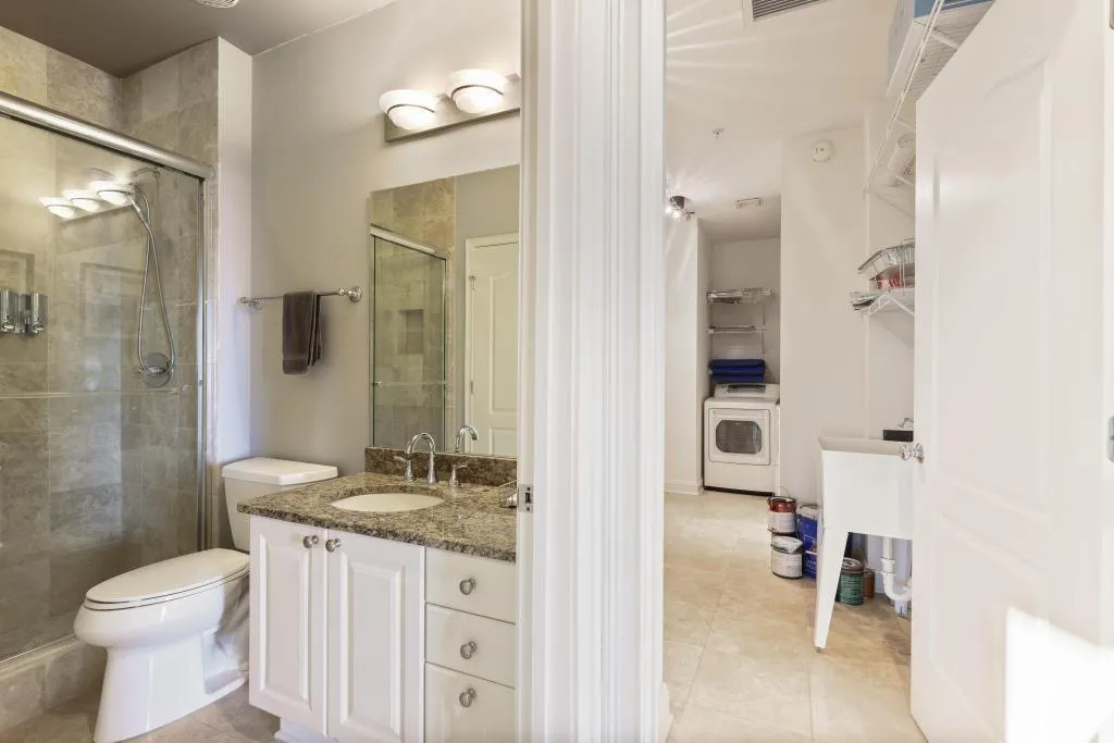 Bathroom featuring tile patterned flooring, washer / clothes dryer, vanity, a shower with shower door, and toilet