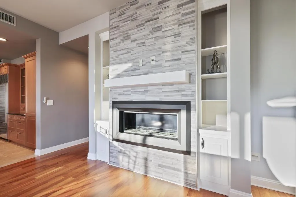 Unfurnished living room with built in features, light wood-type flooring, and a tiled fireplace