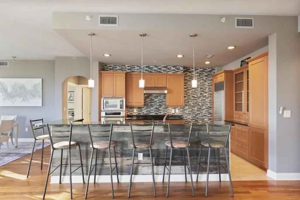 Kitchen with a kitchen bar, light hardwood / wood-style floors, hanging light fixtures, a spacious island, and appliances with stainless steel finishes