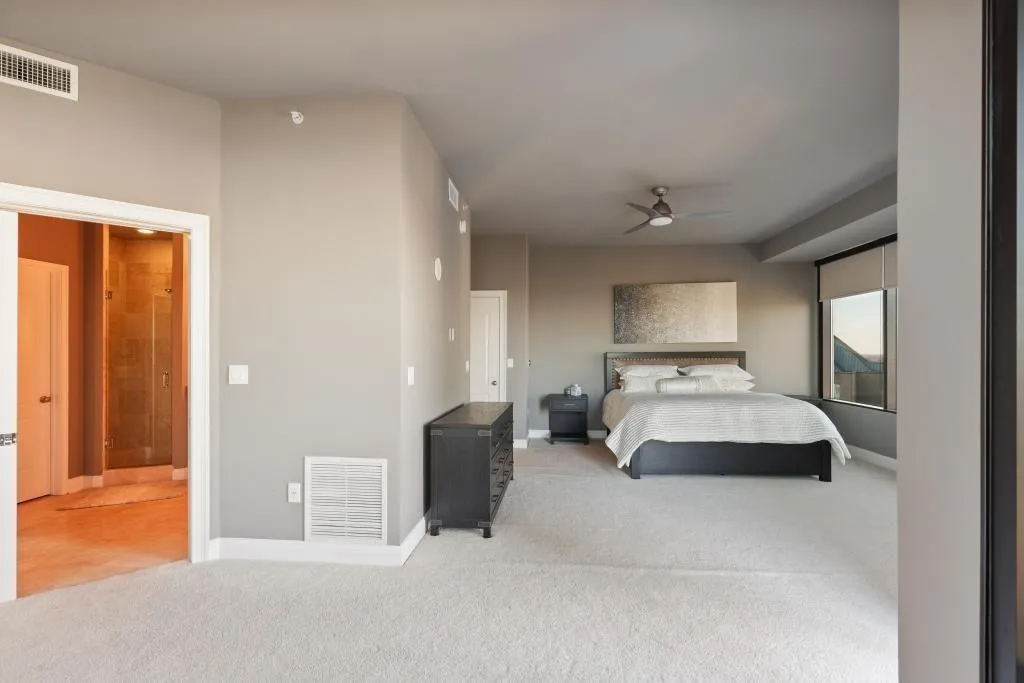 Bedroom with light colored carpet, ceiling fan, and ensuite bath