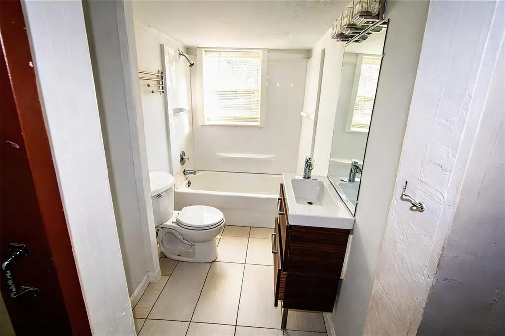 Bathroom with vanity, bathtub / shower combination, and light tile patterned floors