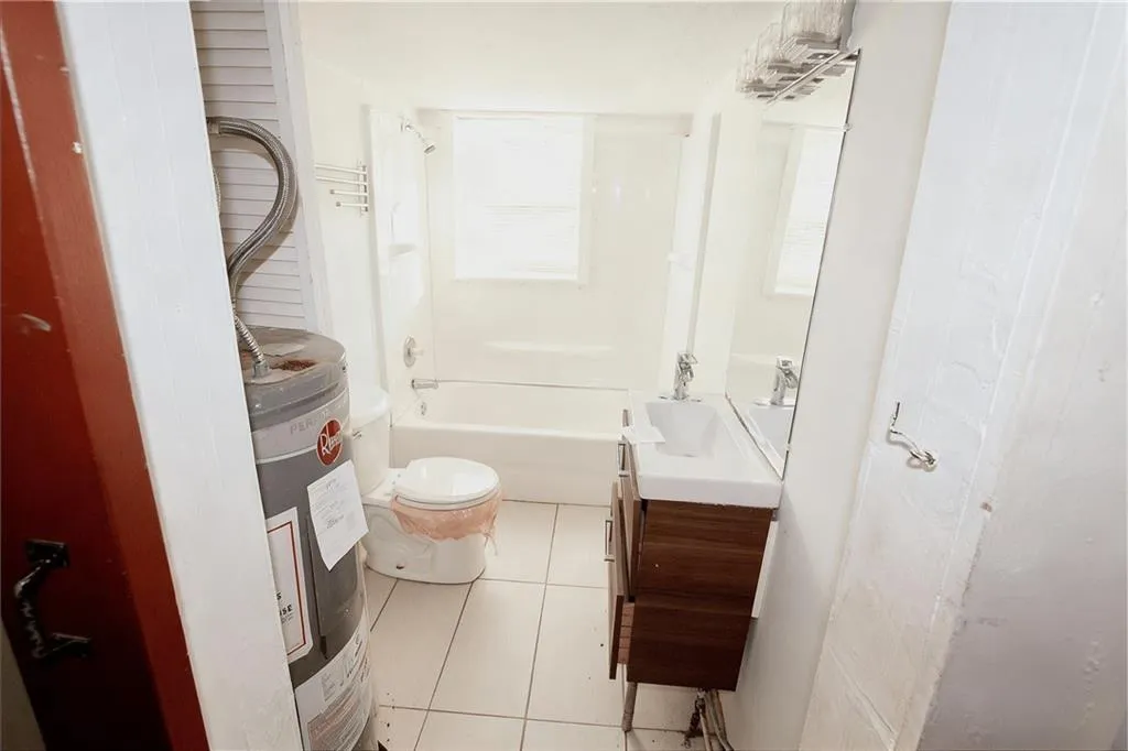 Bathroom featuring light tile patterned floors, vanity, water heater, and shower / bathtub combination