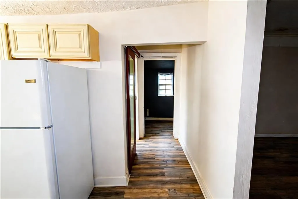 Hallway featuring dark wood finished floors and baseboards