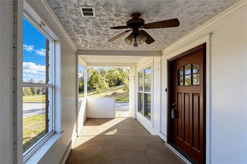 View of exterior entry featuring a sunroom, ceiling fan, and a baseboard heating unit