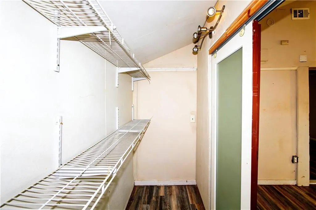 Walk in closet featuring dark wood-type flooring and lofted ceiling