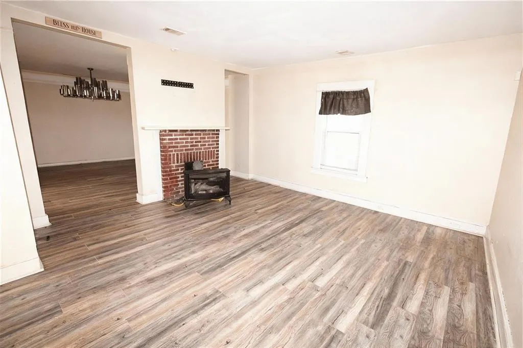 Unfurnished living room featuring wood finished floors and a wood stove