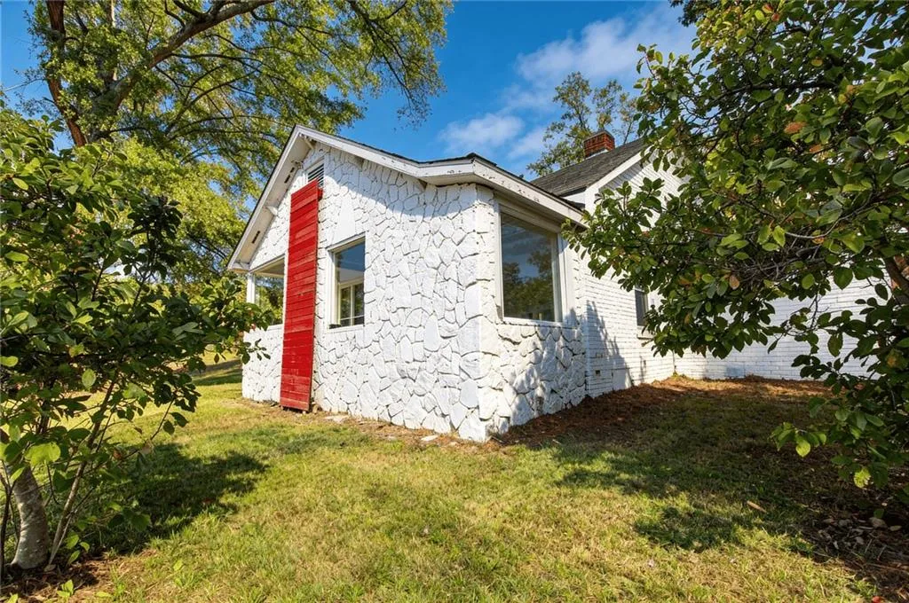 View of side of property featuring a yard, a chimney, and stone siding