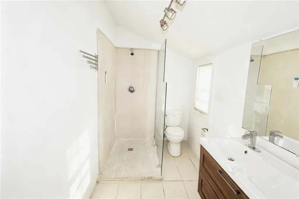 Full bath featuring light tile patterned floors, vanity, and a shower stall