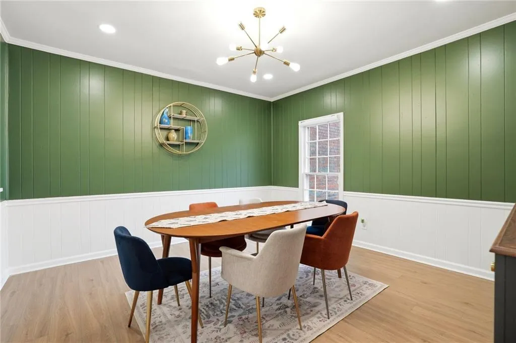 Dining area with ornamental molding, a chandelier, wood finished floors, and wooden walls