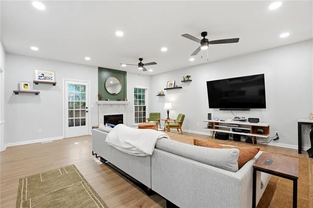 Living area with light wood finished floors, a high end fireplace, recessed lighting, and ceiling fan