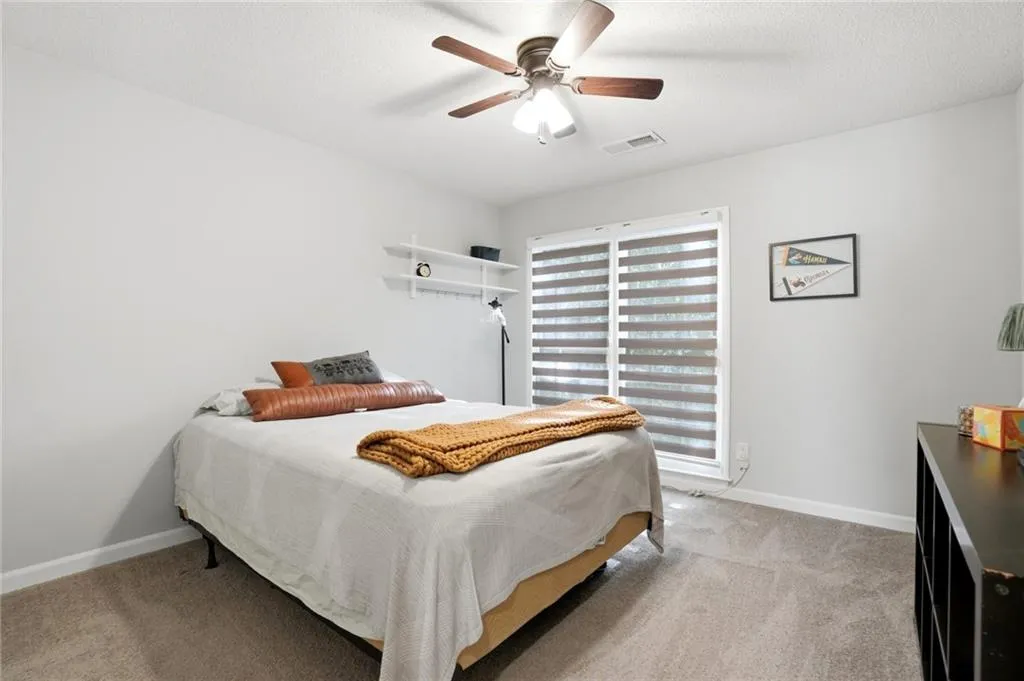 Bedroom with light carpet, a ceiling fan, and a textured ceiling