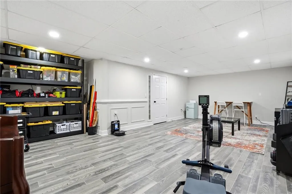 Exercise area with recessed lighting, a paneled ceiling, light wood-style flooring, a wainscoted wall, and a decorative wall