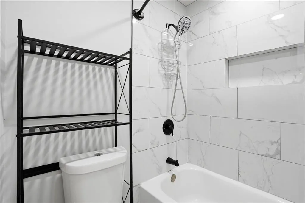 Full bathroom featuring toilet and washtub / shower combination