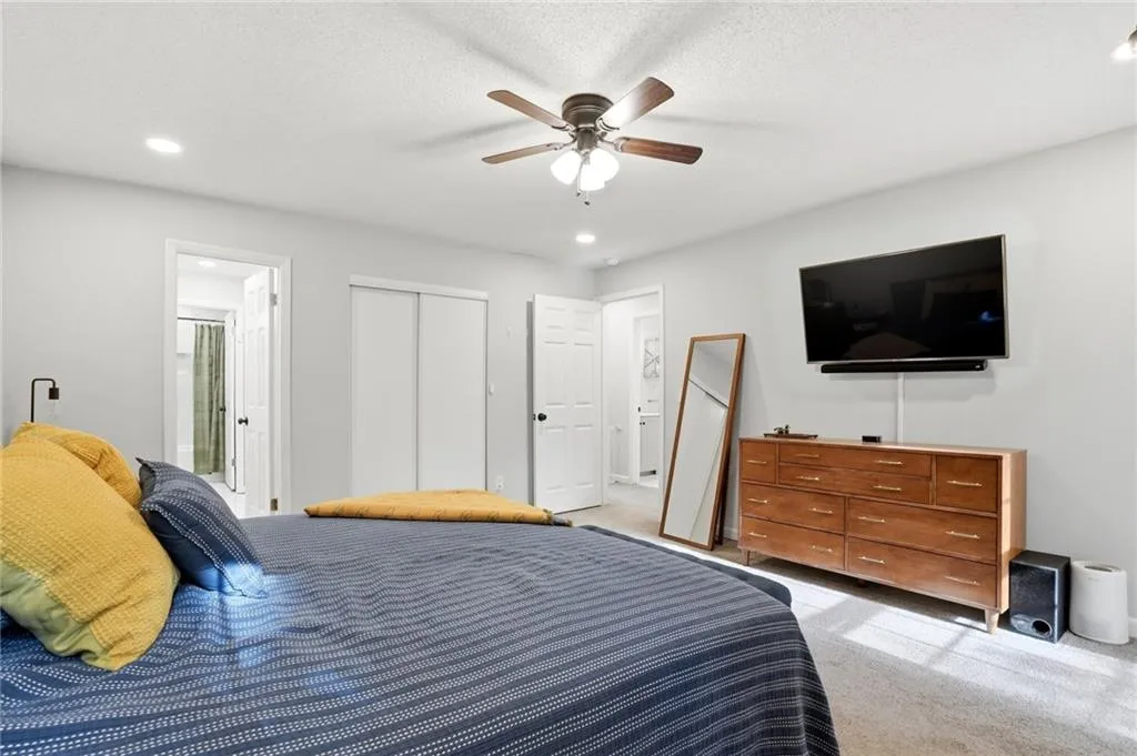 Bedroom with recessed lighting, carpet floors, ceiling fan, ensuite bathroom, and a textured ceiling