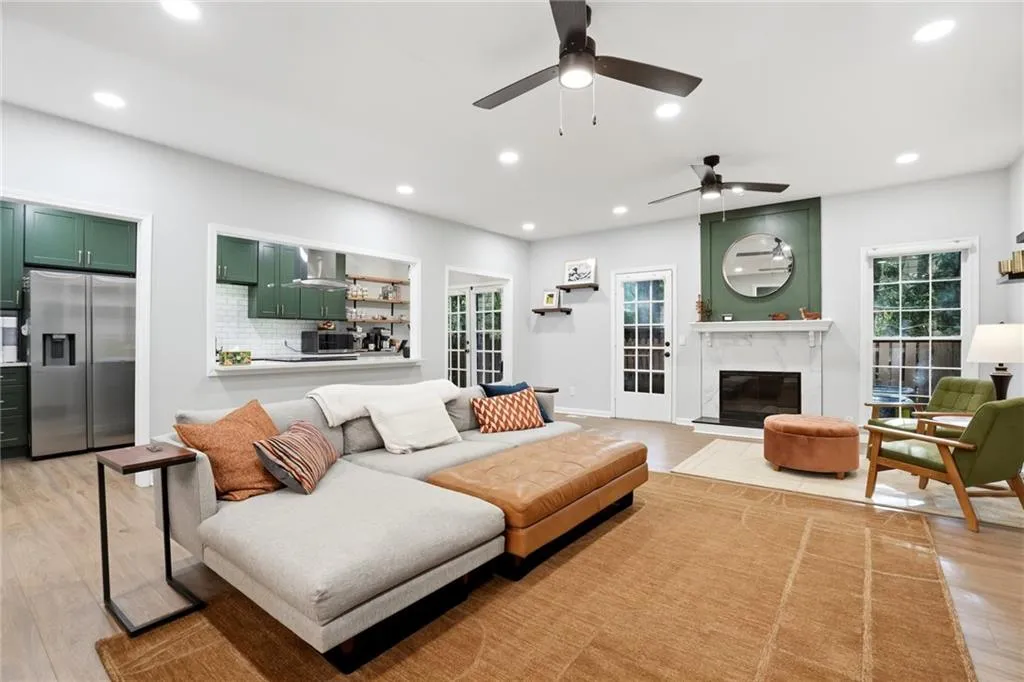 Living room featuring light wood-style flooring, a premium fireplace, recessed lighting, ceiling fan, and plenty of natural light