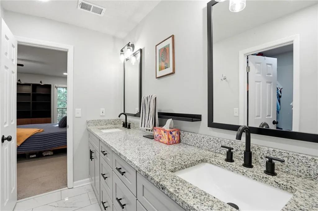 Ensuite bathroom with double vanity and light marble finish floors
