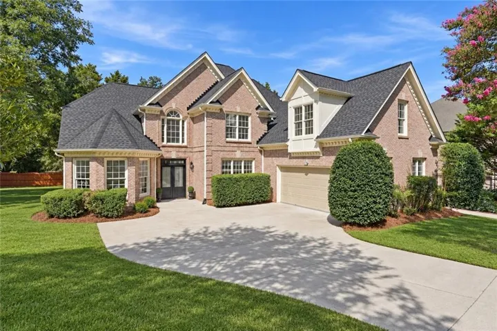 Brick exterior with multiple gables, arched windows, a two-car garage, and a concrete driveway