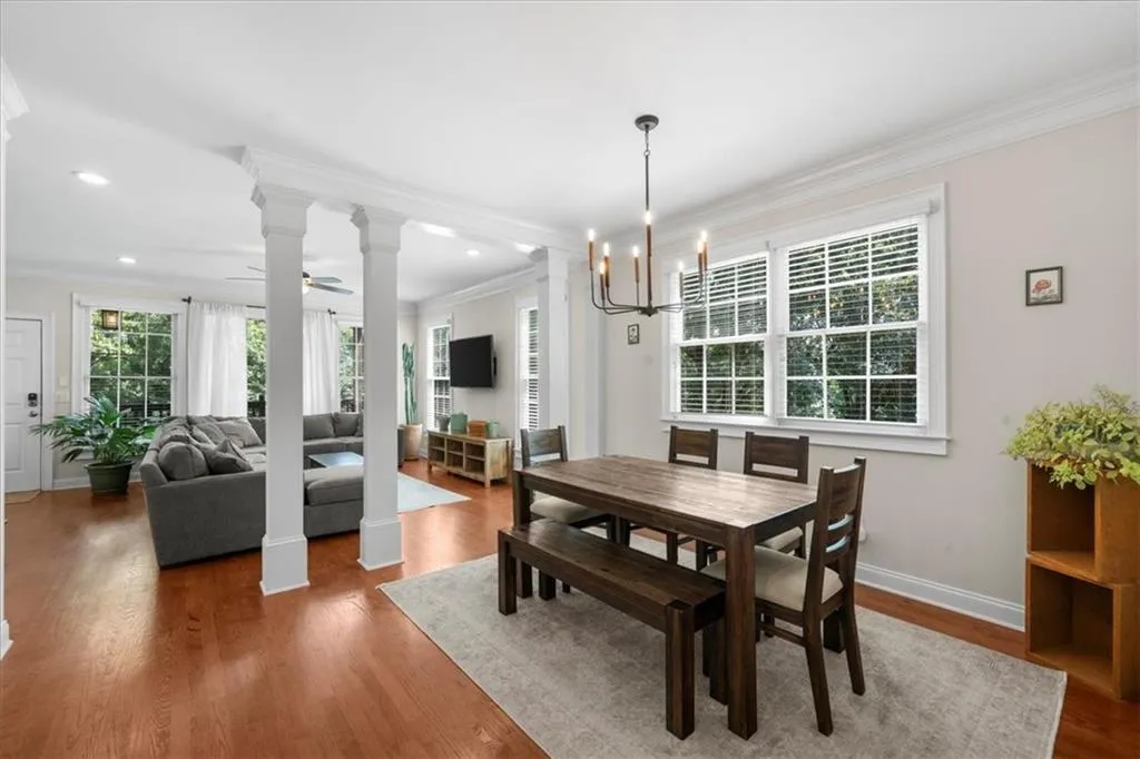 Dining room featuring ornamental molding, a chandelier, decorative columns, wood finished floors, and a ceiling fan