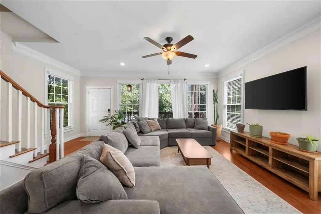 Living area with crown molding, stairs, wood finished floors, ceiling fan, and recessed lighting