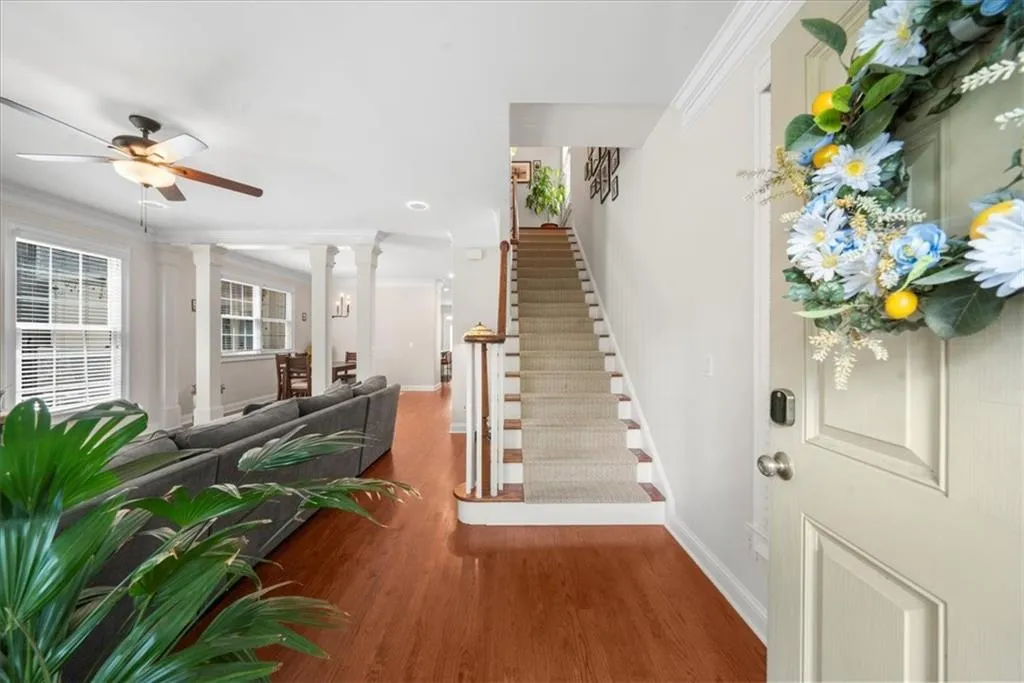 Foyer featuring crown molding, wood finished floors, ceiling fan, and stairway