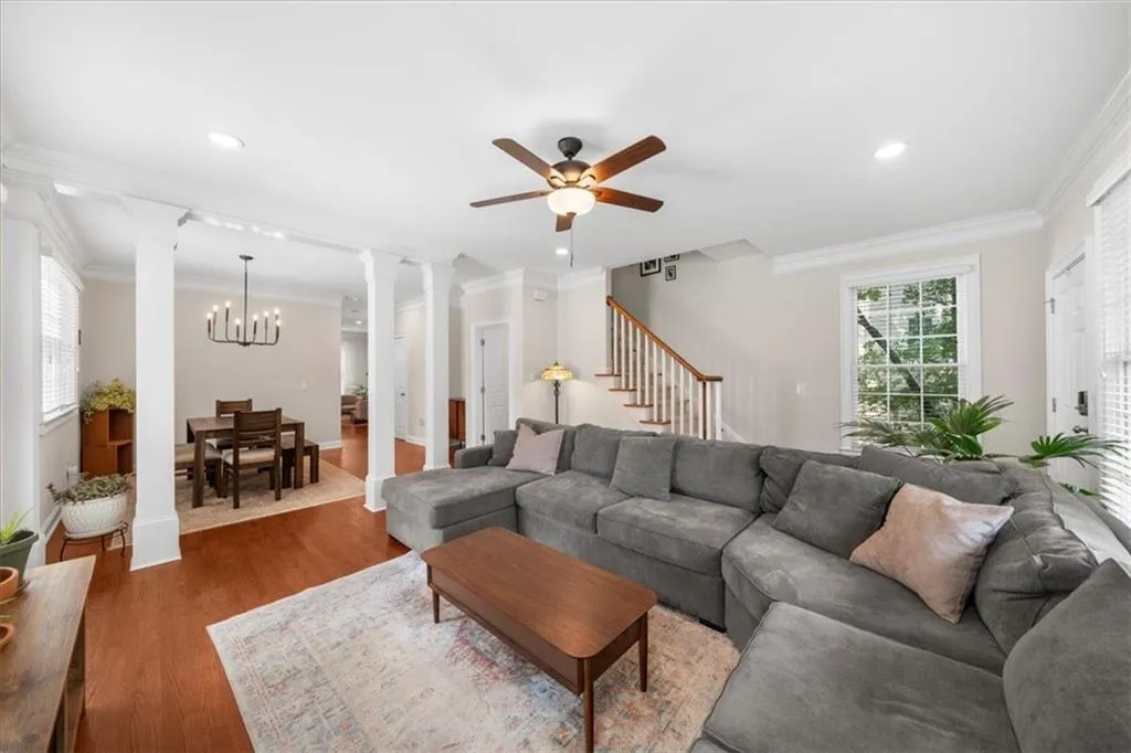 Living room featuring decorative columns, ceiling fan, crown molding, wood finished floors, and recessed lighting