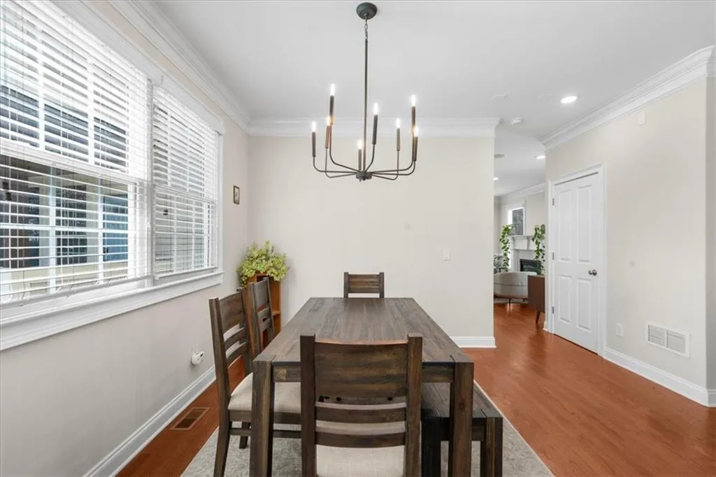 Dining area with a chandelier, wood finished floors, crown molding, and recessed lighting