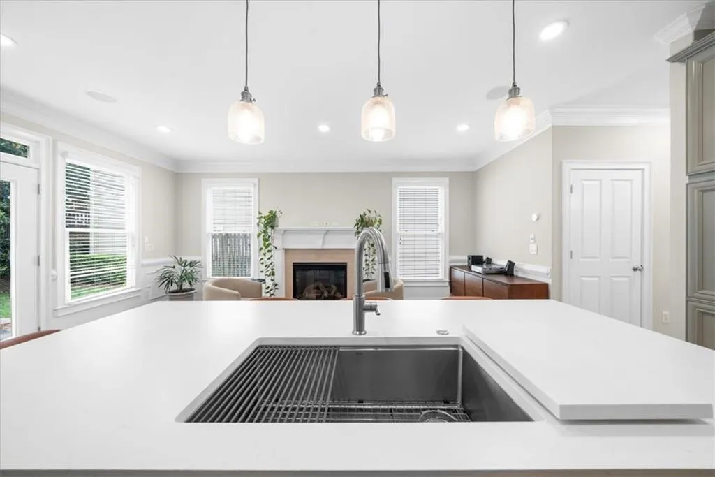 Kitchen with a glass covered fireplace, light countertops, open floor plan, ornamental molding, and hanging light fixtures