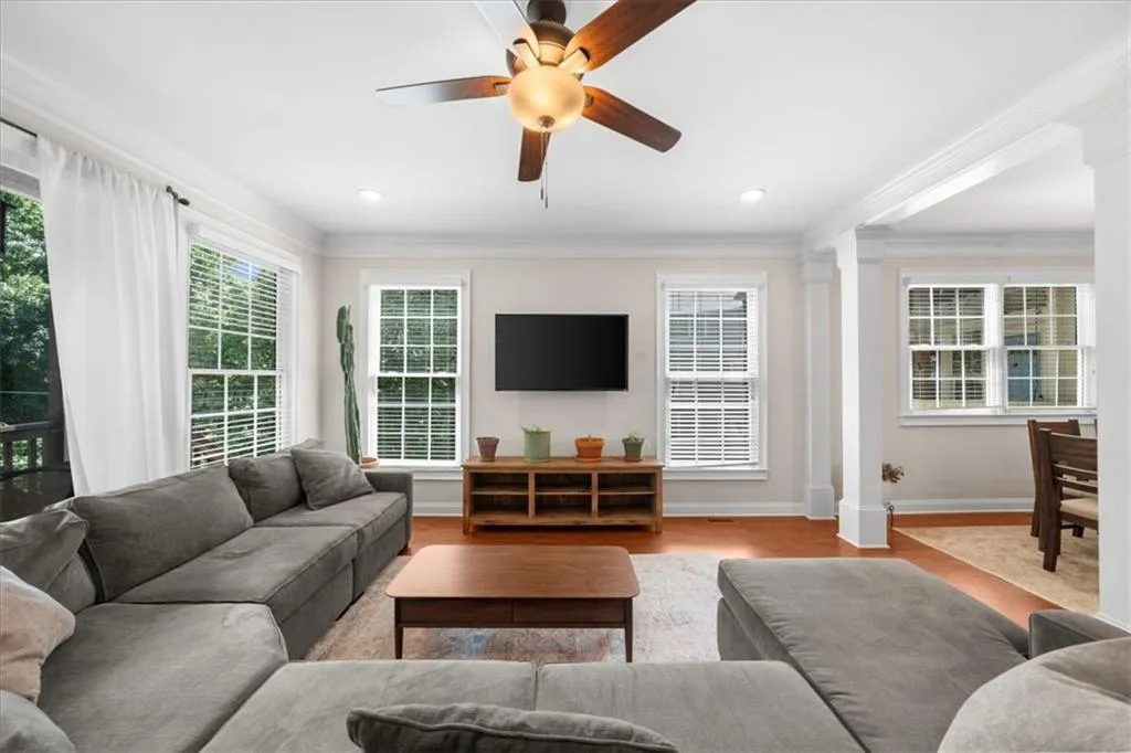 Living room featuring ornate columns, wood finished floors, a ceiling fan, ornamental molding, and recessed lighting