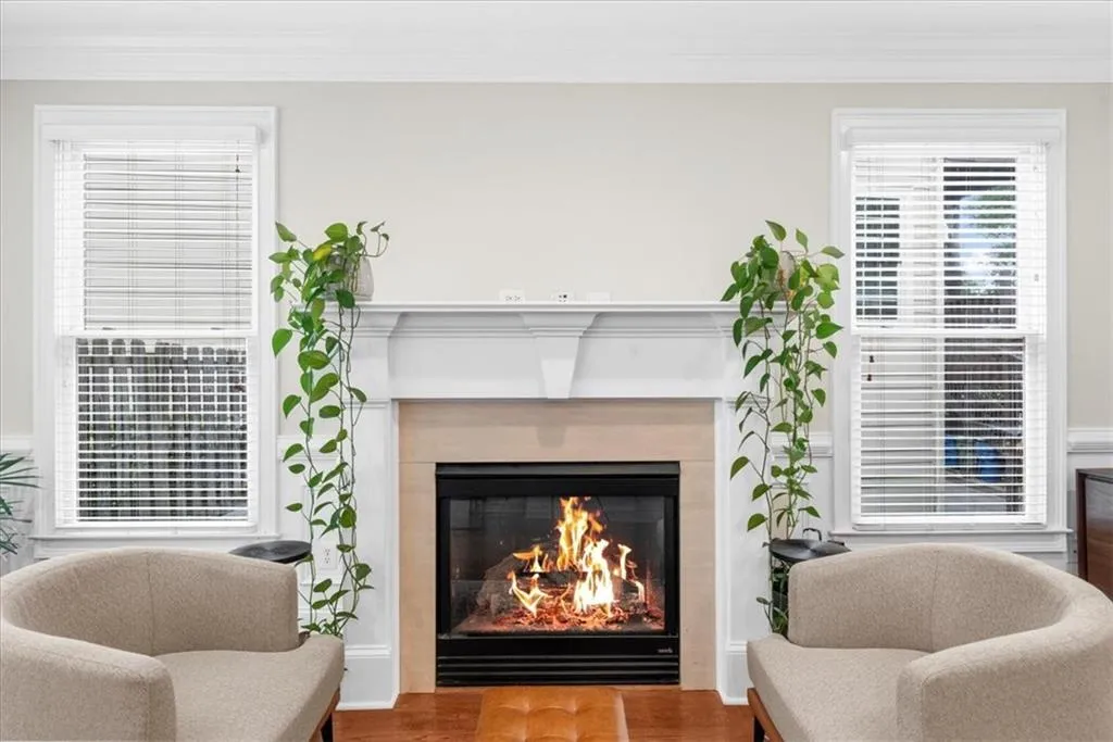 Detailed view of a glass covered fireplace, ornamental molding, and wood finished floors