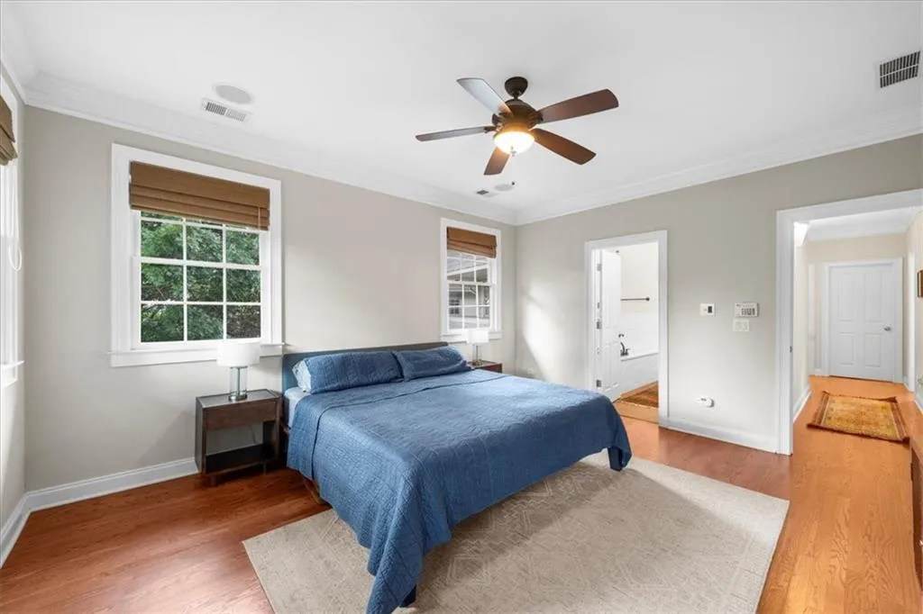 Bedroom with crown molding, wood finished floors, a ceiling fan, and ensuite bath