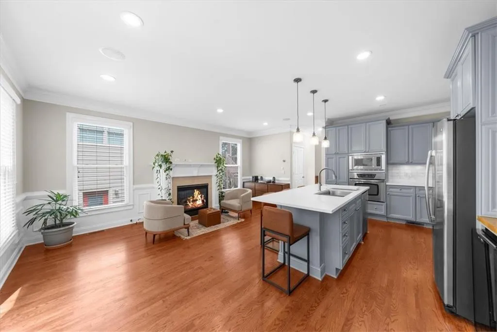 Kitchen with stainless steel appliances, gray cabinetry, open floor plan, a kitchen bar, and an island with sink