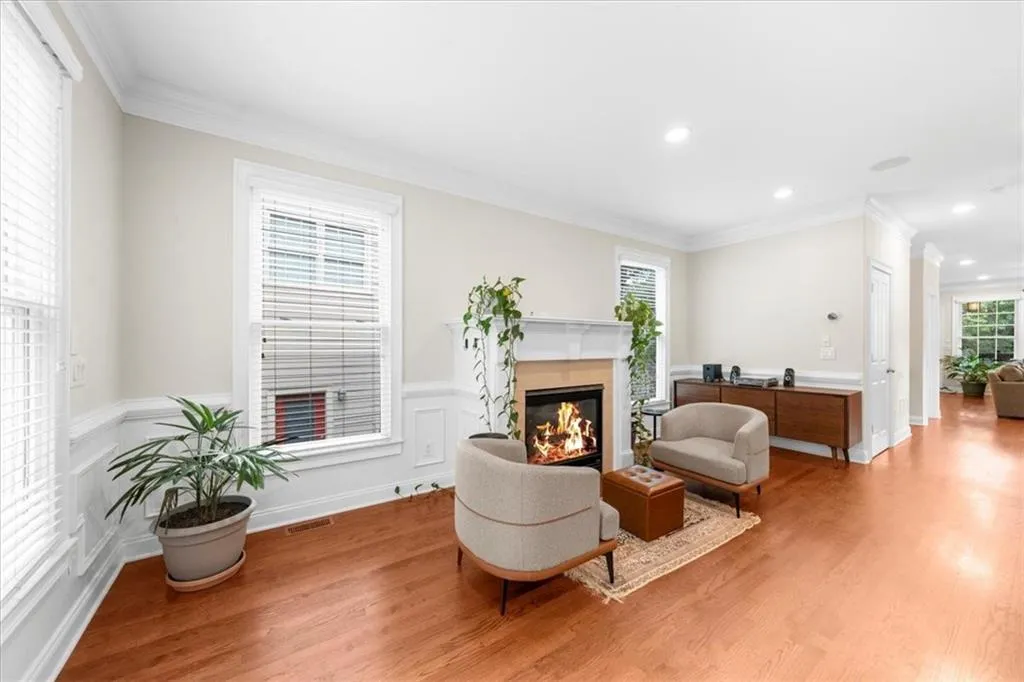 Living area with light wood finished floors, a premium fireplace, crown molding, and recessed lighting