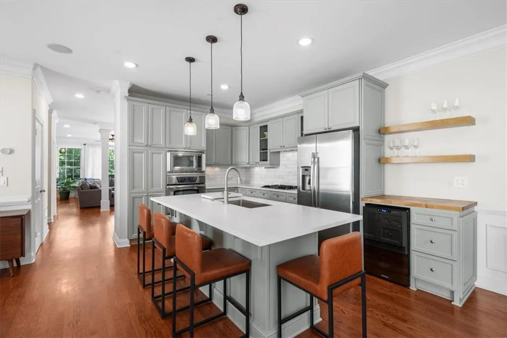 Kitchen with beverage cooler, gray cabinetry, stainless steel appliances, ornamental molding, and decorative backsplash
