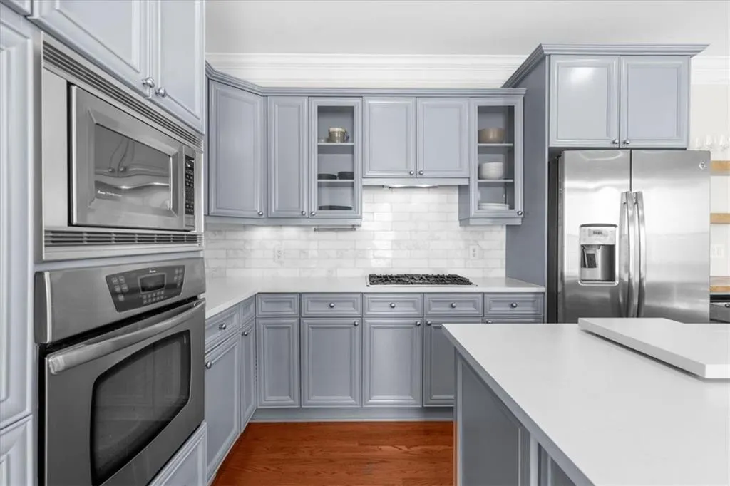 Kitchen with appliances with stainless steel finishes, gray cabinetry, light countertops, and tasteful backsplash