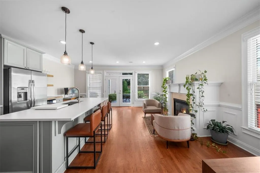 Kitchen with stainless steel fridge, light wood-style floors, a glass covered fireplace, light countertops, and ornamental molding
