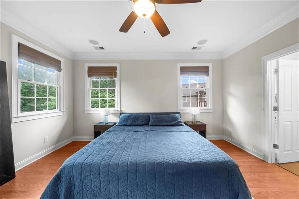 Bedroom with light wood-style floors, ornamental molding, and a ceiling fan