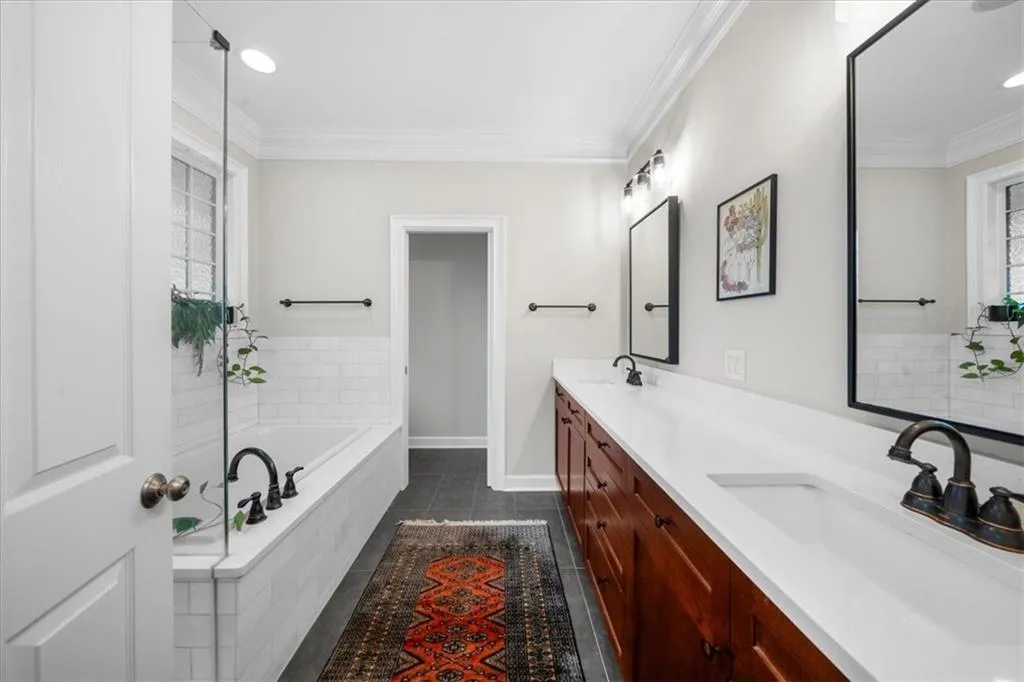 Full bath with double vanity, healthy amount of natural light, a garden tub, tile patterned flooring, and ornamental molding