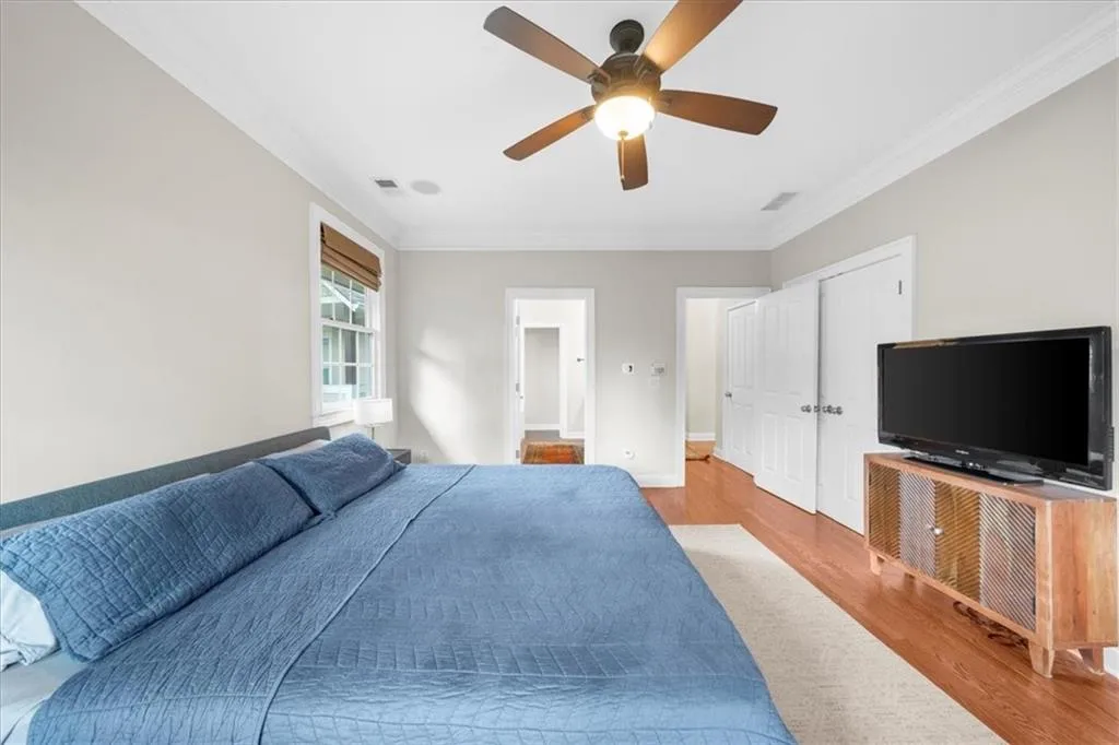 Bedroom featuring wood finished floors, crown molding, and a ceiling fan