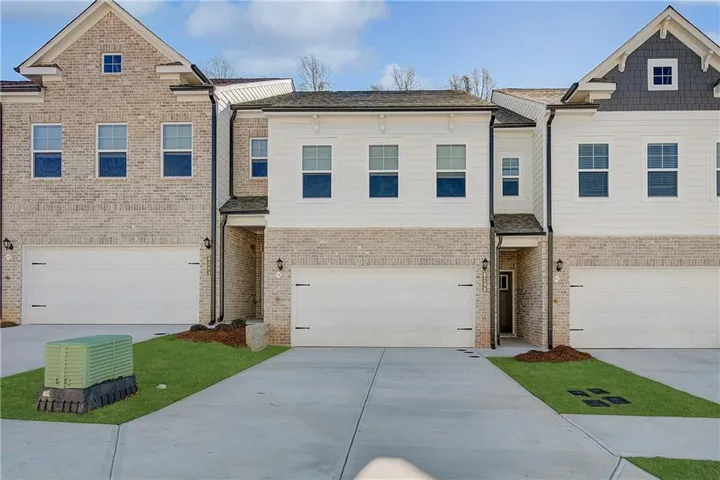 Contemporary townhome exterior featuring light brick and white siding