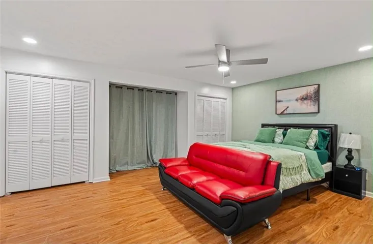 Wood-finish flooring with recessed lighting, louvered closet doors, and ceiling fan
